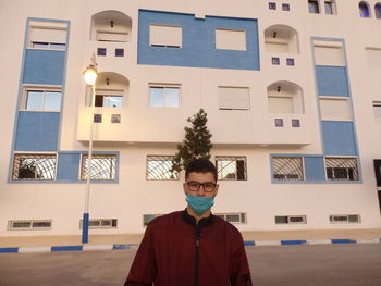 Portrait of man standing against building in city