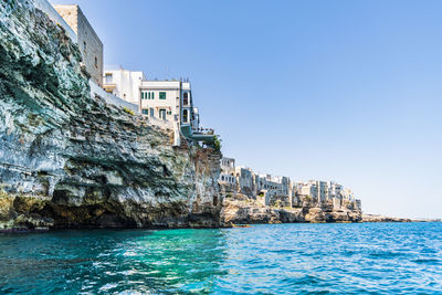 Sea by buildings against clear blue sky