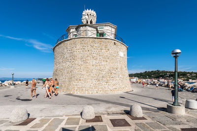 People at historical building against blue sky