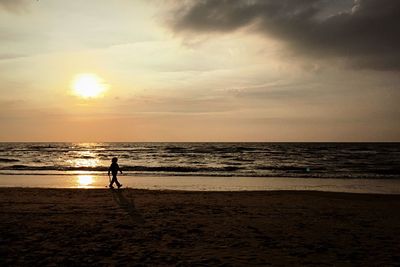 Man on beach against sky during sunset