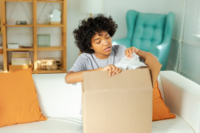 Portrait of young woman using digital tablet while sitting on sofa at home