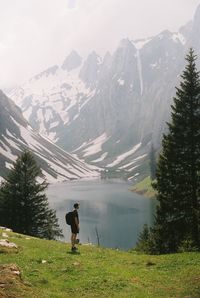 Rear view of man standing on mountain in front of a lake