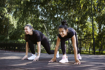 Girl in sportswear on a sunny summer day on the embankment in the park doing fitness and stretching