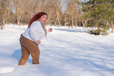 Portrait of young woman standing on snow covered field