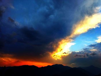 Scenic view of dramatic sky over silhouette mountains