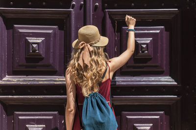 Rear view of woman standing against door