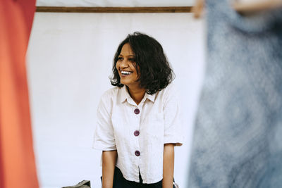 Happy female owner standing in stall at flea market