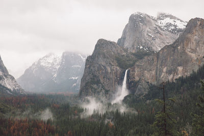 Scenic view of waterfall and mountains against sky