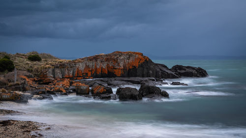Rock formation by sea against sky