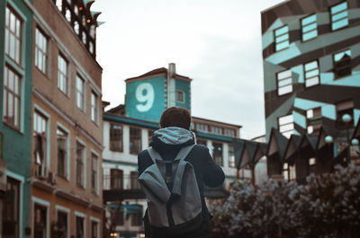 Rear view of woman standing against sky in city
