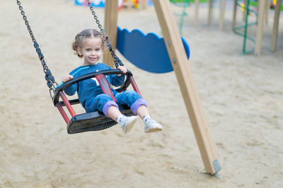 Full length portrait of girl enjoying on swing