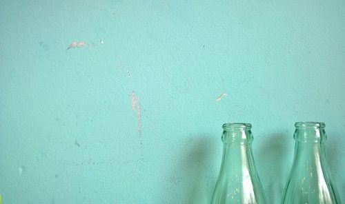 Close-up of bottles against turquoise wall