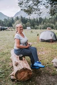 Woman sitting on tent in field