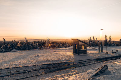 Snow covered railroad tracks against sky during sunset
