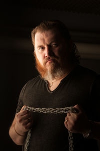 Man looking away while standing against black background