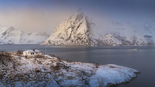 Frozen lake by snowcapped mountain against sky