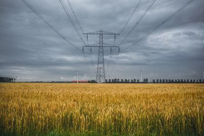 View of field with electricity pylon and windmill