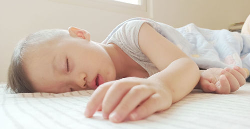 Close-up of baby sleeping on bed at home