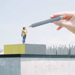 Low angle view of woman holding umbrella standing against building