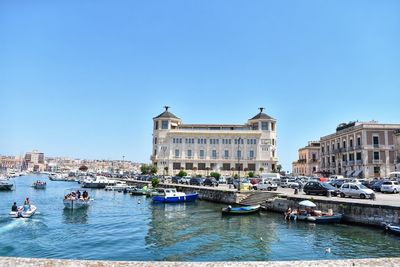 Boats in river against buildings in city