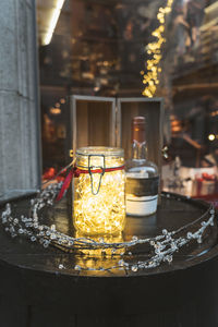 Illuminated christmas lights in jar on table at home