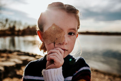 Portrait of a girl with a leaf covering half of her face