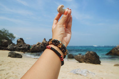 Cropped hand of woman holding stone at beach