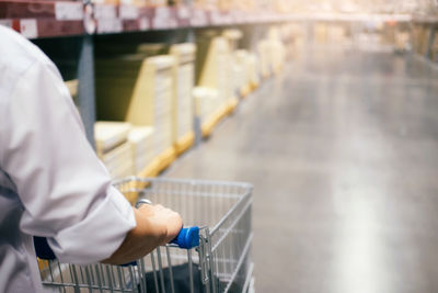 Midsection of man holding shopping cart while standing in supermarket