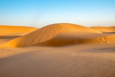 Sand dunes in desert against clear sky