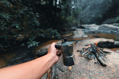 Person holding cigarette in forest