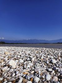 Surface level of stones on beach against clear blue sky