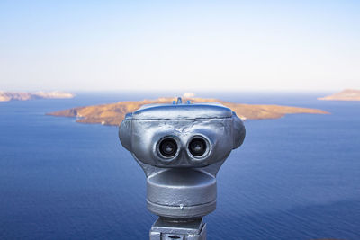 Close-up of coin-operated binoculars by sea against sky