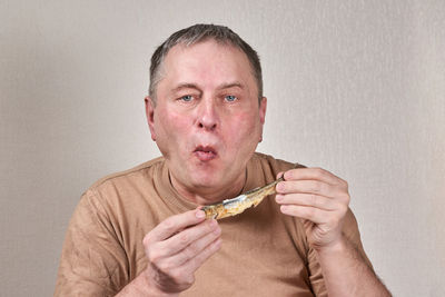 Portrait of man eating food against white background