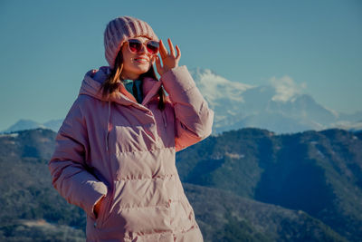 Portrait of young man wearing sunglasses standing on mountain