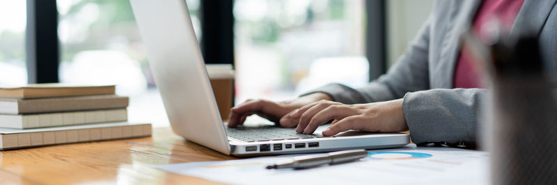 Midsection of woman using laptop on table