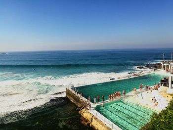 People at beach against clear blue sky