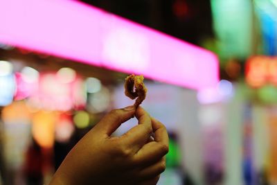 Cropped hand holding food at night