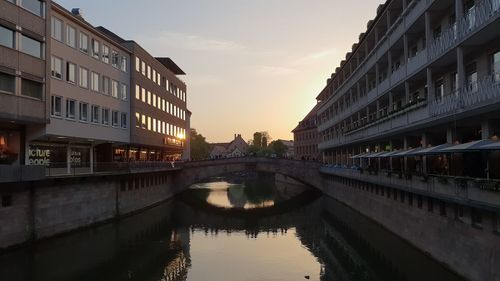 Bridge over canal amidst buildings in city against sky