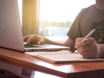 Midsection of man using laptop on table