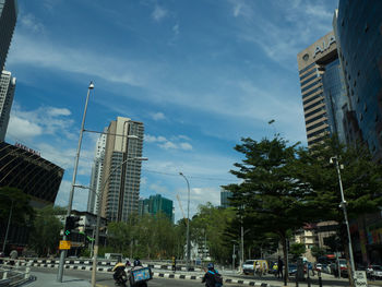 Cars on city street by buildings against sky