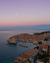 High angle view of townscape by sea against sky during sunset