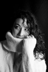 Portrait of young woman against black background