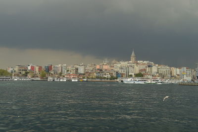 Sea by city buildings against sky