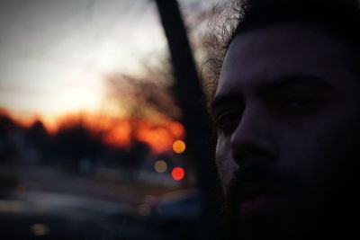 Close-up portrait of man in car against sky during sunset