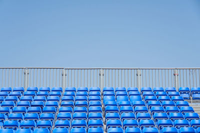 Low angle view of empty chairs against clear blue sky