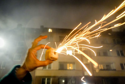 Close-up of hand holding illuminated firework display at night