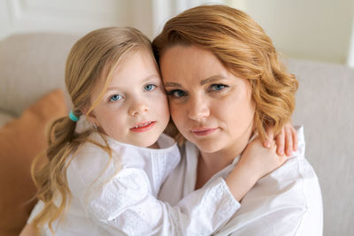 Portrait happy family, single mother and baby daughter hugging on sofa at home