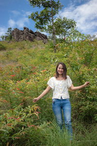 Portrait of smiling woman standing amidst plants on land