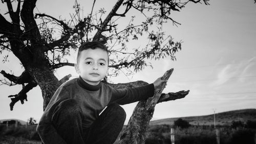 Portrait of boy crouching on tree