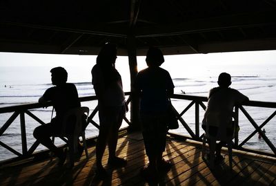 Silhouette people standing by sea against sky